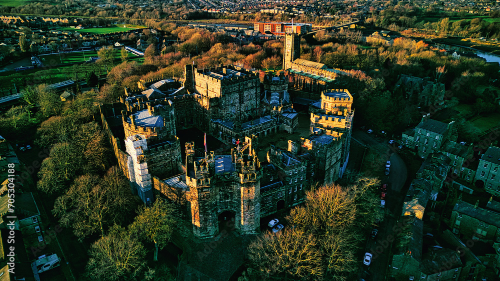 Aerial view of the Lancaster castle surrounded by greenery at sunset, showcasing the architecture and landscape.