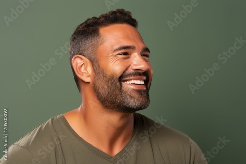 Portrait of a handsome young man laughing and looking at camera against green background