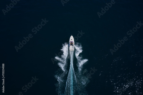 Large high-speed White boat with people moving quickly on dark water, top view. © Berg
