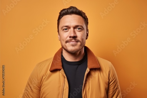 Portrait of a handsome young man in a yellow jacket on a yellow background.