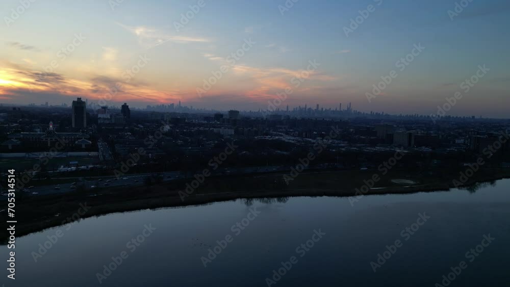nyc skyline at sunset (aerial drone shot from far away distance in queens) corona flushing meadows park with meadow lake in foreground (setting sun, glow, golden hour) still shot footage nyc skyline at sunset (aerial drone shot from far away distance in queens) corona flushing meadows park with meadow lake in foreground (setting sun, glow, golden hour) still shot footage