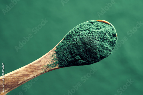 Spirulina powder on a spoon, top view. Nutritional supplement.