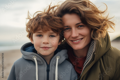 mother and son wearning jackets on a cold windy beach photo