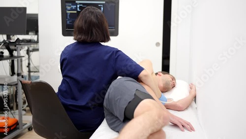 Video of a male patient lying while female cardiologist performing an echocardiogram photo