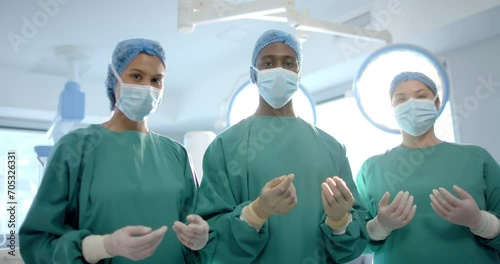 Portrait of three diverse male and female surgeons in operating theatre, slow motion photo