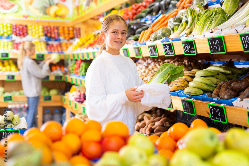 Teenage girl customer buying lettuce at grocery supermarket