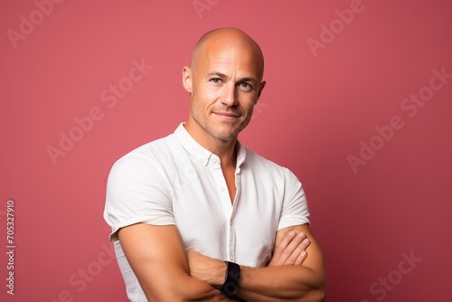 Portrait of a handsome bald man with crossed arms on a pink background