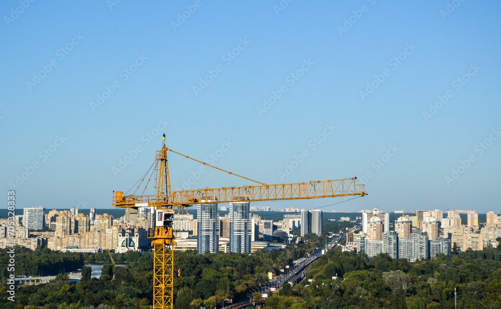 High construction crane with left bank city districts on the background. Urban skyline of Kyiv, Ukraine 