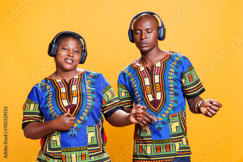 African american couple listening to music in wireless headphones and pretending to play guitar. Black man and woman wearing eraphones enjoying song together and looking at camera photo