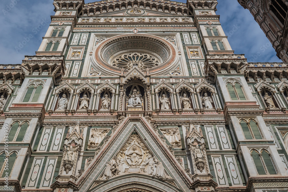 Detail of the facade of Santa Maria del Fiore cathedral with carved saints in Gothic niches and rose window, Florence ITALY
