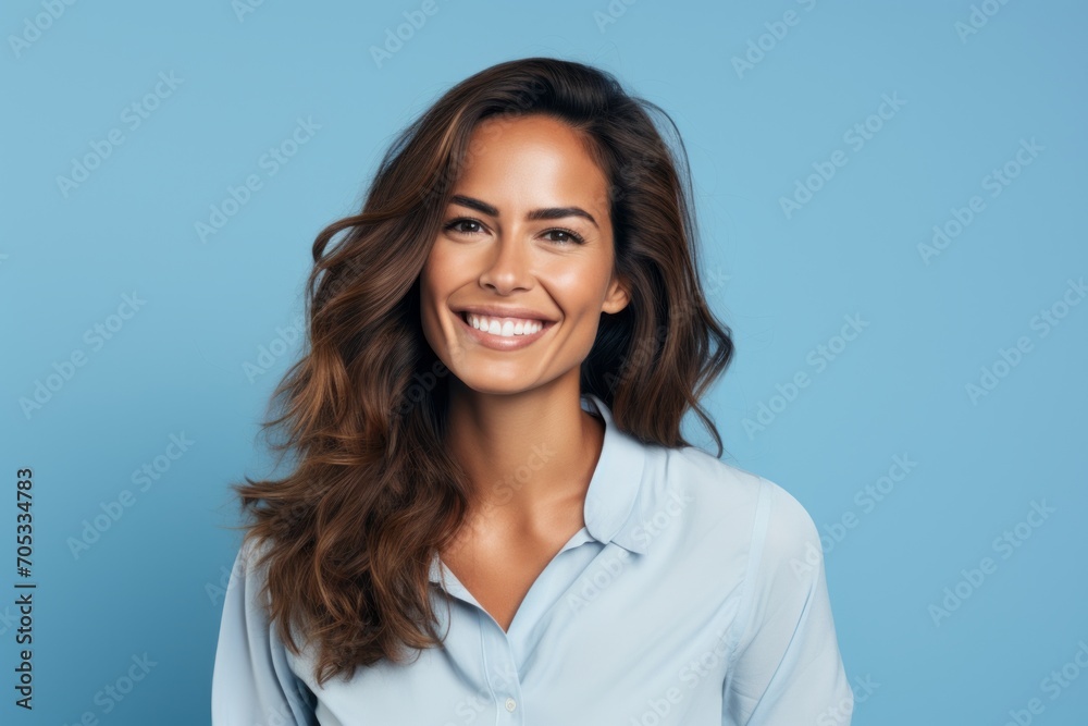 Portrait of happy smiling young business woman in blue shirt, over blue background
