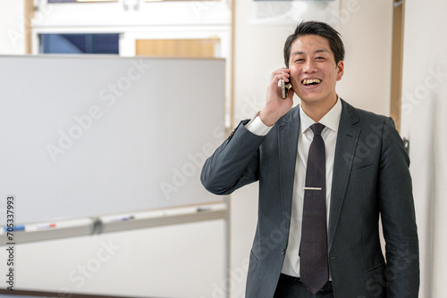 ボード前で電話するスーツの男性 photo