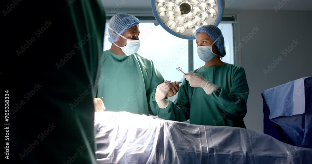 Diverse female and male surgeons in masks passing surgical tools during operation, slow motion