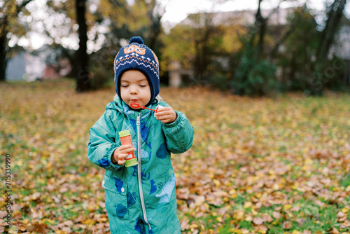 Little girl blowing soap bubbles standing in autumn park