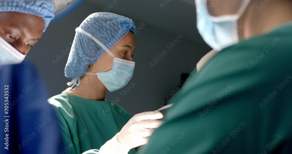 Diverse female and male surgeons in masks passing surgical tools during operation, slow motion