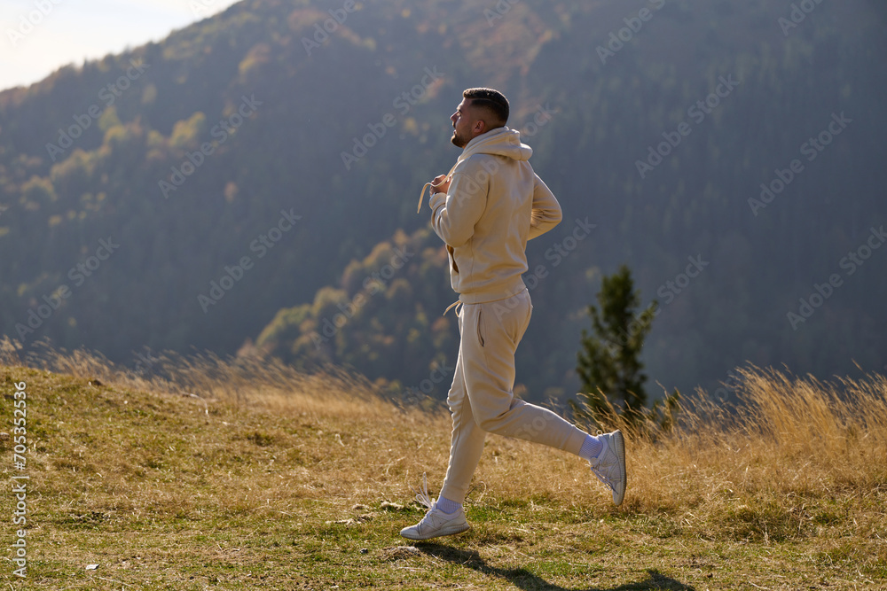 Obraz premium A handsome man maintains his healthy lifestyle as he runs along beautiful natural trails, embodying the essence of fitness, wellness, and vitality in the midst of scenic outdoor surroundings.