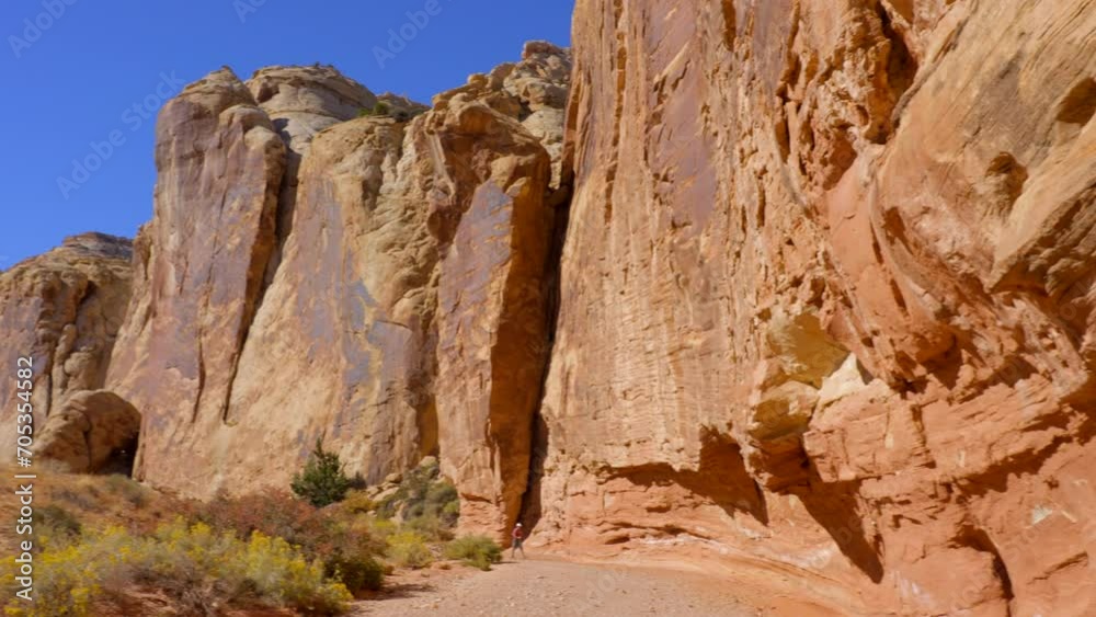 Establishing shot of mountain trail with red rocks in Grand Wash Trail, Capital Reef National Park, Utah, North America. Day time on October 2023. ProRes 422 HQ. Establishing shot of mountain trail with red rocks in Grand Wash Trail, Capital Reef National Park, Utah, North America. Day time on October 2023. ProRes 422 HQ.
