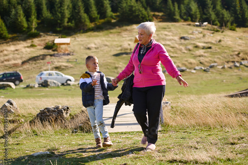 Fototapeta Elderly grandmother and her grandchild share a leisurely stroll through nature,