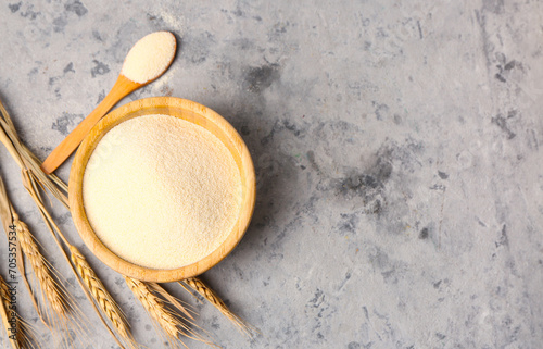 Bowl with raw semolina on grunge background