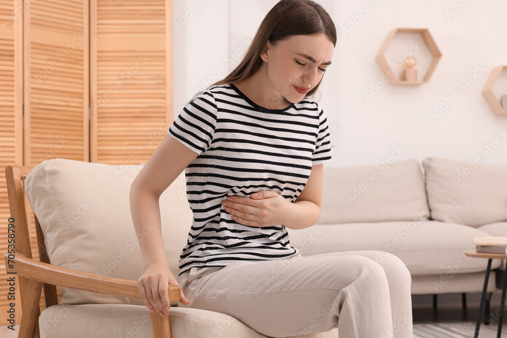 Young woman suffering from stomach pain at home Young woman suffering from stomach pain at home
