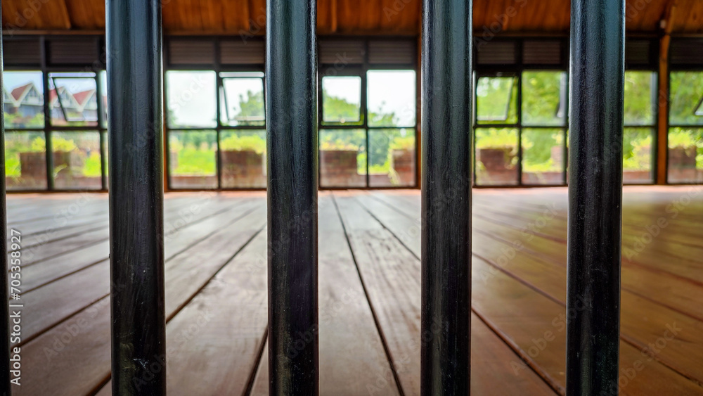 The room had a wooden floor, blocked by black iron bars The room had a wooden floor, blocked by black iron bars