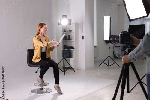 Casting call. Woman with script performing while camera operator filming her against light grey background in studio