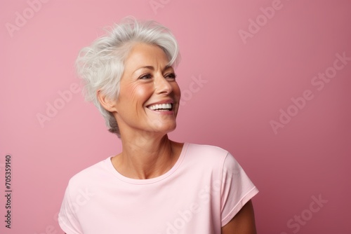 Portrait of a happy senior woman smiling against pink background with copy space