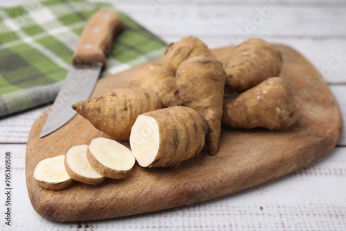 Whole and cut turnip rooted chervil tubers on light wooden table, closeup photo