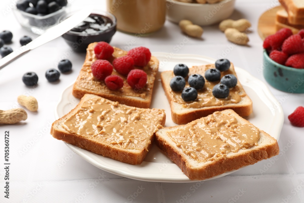 Delicious toasts with peanut butter, raspberries and blueberries on white table, closeup Delicious toasts with peanut butter, raspberries and blueberries on white table, closeup