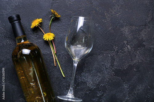 Bottle and glass of dandelion wine on black background