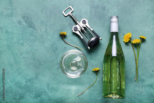 Bottle and glass of dandelion wine on green background
