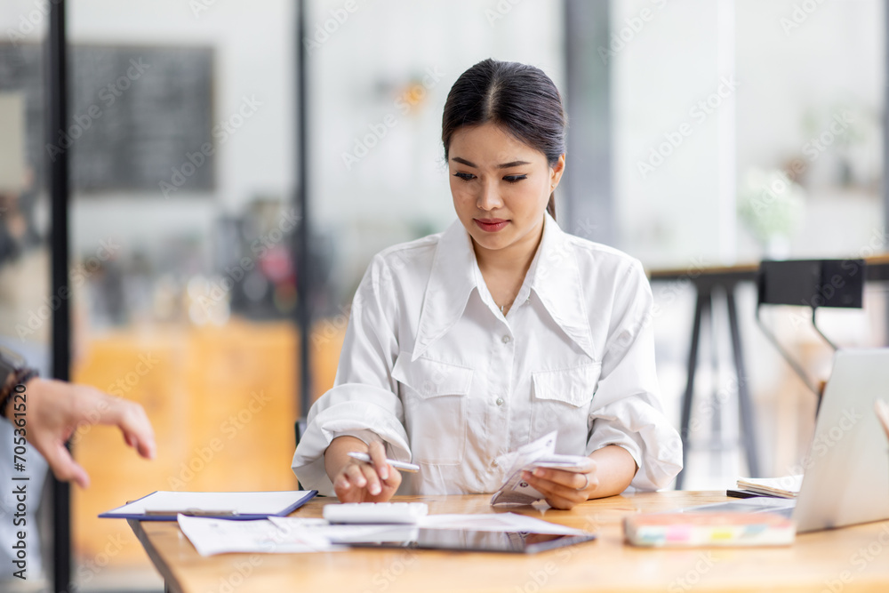 asian woman using calculator and calculate bills in home office. tax form us business income office Financial document. Tax time.Tax concept.