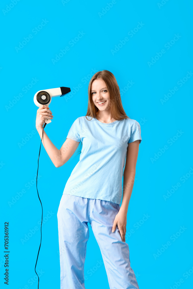 Beautiful young woman with hair dryer on light blue background Beautiful young woman with hair dryer on light blue background