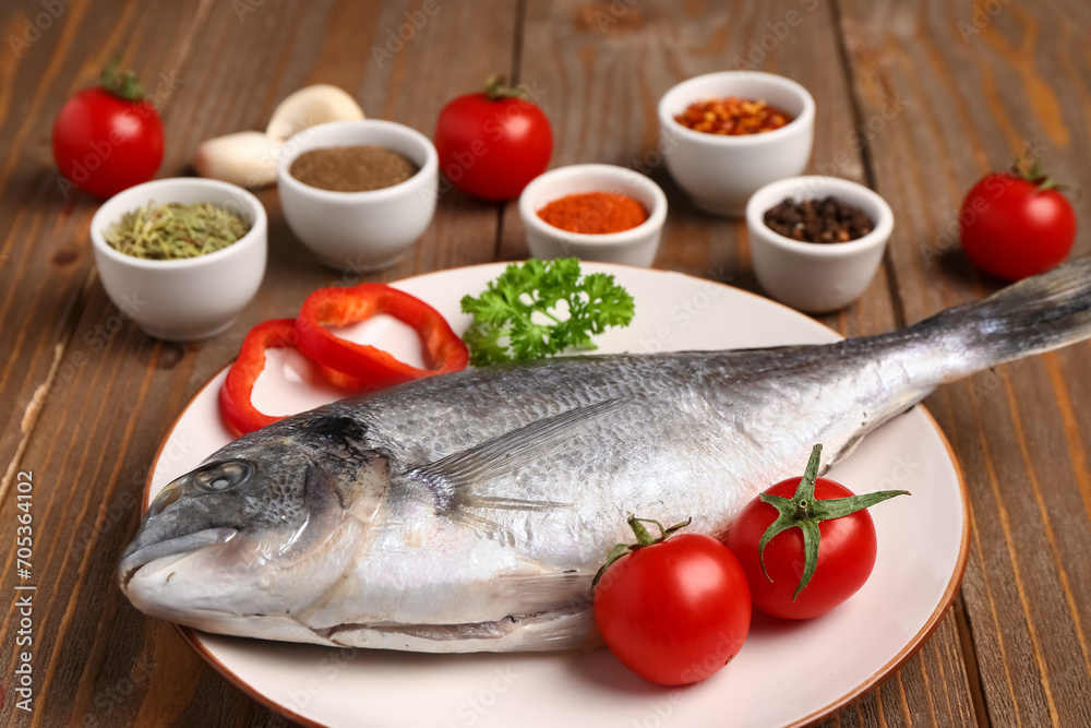 Plate of raw dorado fish with tomatoes on wooden background Plate of raw dorado fish with tomatoes on wooden background