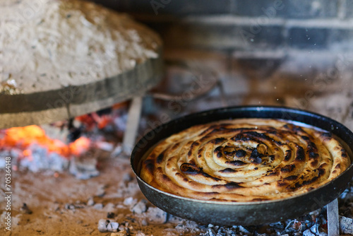 Capturing the essence of Bosnian culinary tradition, step-by-step preparation of a traditional Bosnian pie, showcasing the meticulous craftsmanship and authentic flavors involved in the culinary