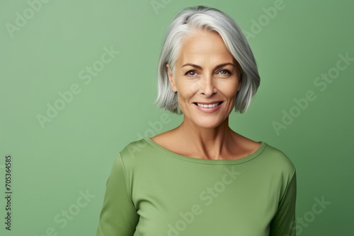 smiling senior woman in green turtleneck looking at camera over green background