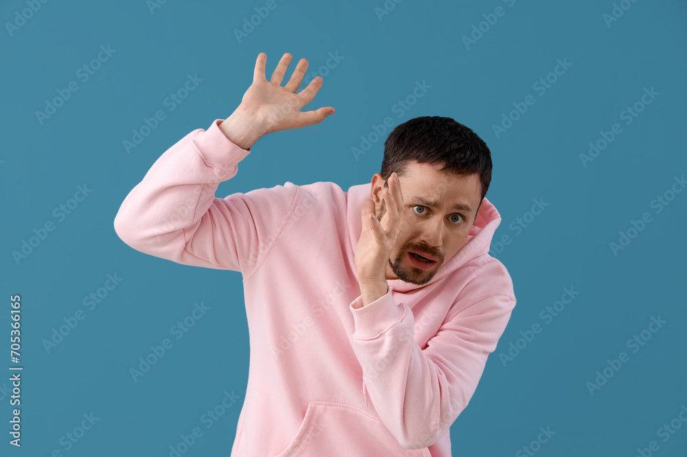 Fototapeta premium Young man having panic attack on blue background