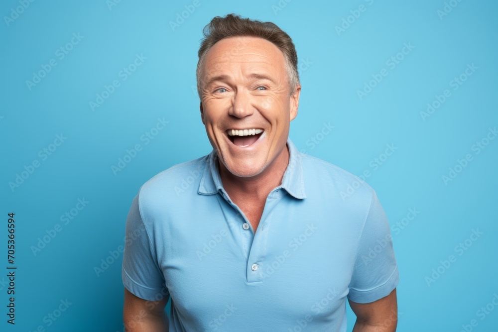 Portrait of happy mature man laughing and looking at camera over blue background