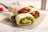 Board of tasty lavash rolls with tomatoes, egg and greens on white marble background