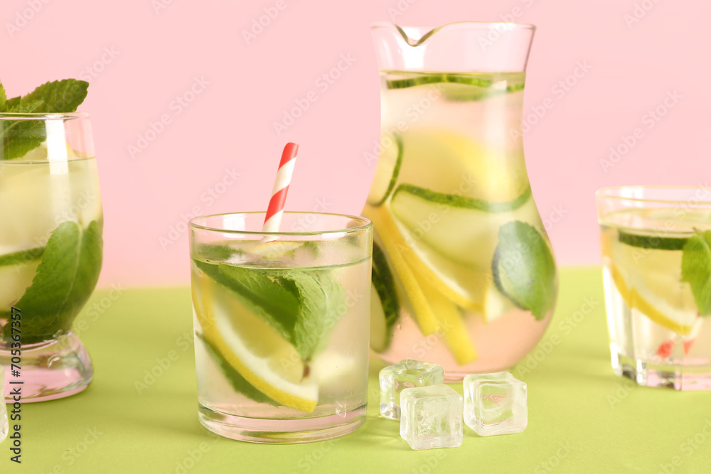 Fototapeta premium Glasses and jug of lemonade with cucumber on green table