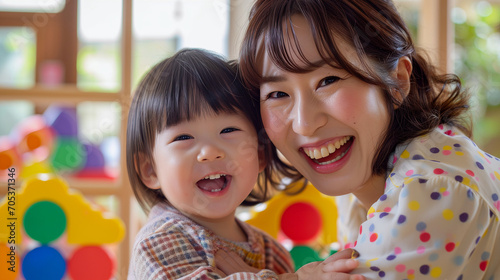 日本の幼稚園児と先生/親子がカラフルなおもちゃで笑顔で遊んでいる写真、背景保育ルーム、木育/幼児教育 photo