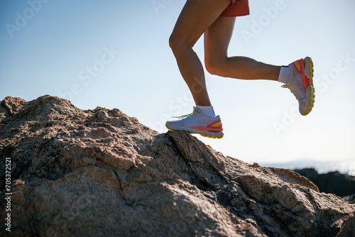 Runner legs running on sunrise seaside rocks