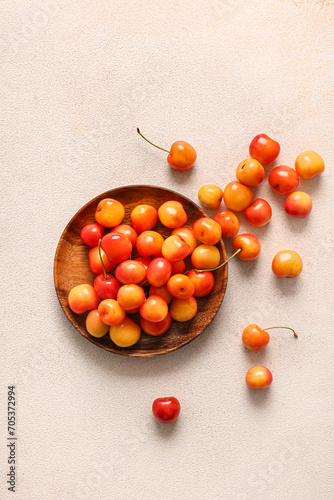 Plate with sweet yellow cherries on white background