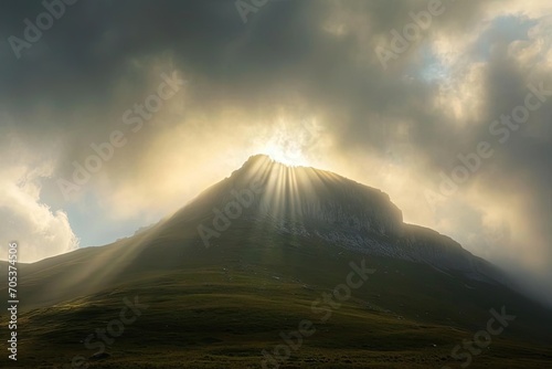 Sunrays breaking through clouds over a solitary mountain