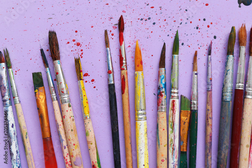 Artist's brushes with paints on lilac background