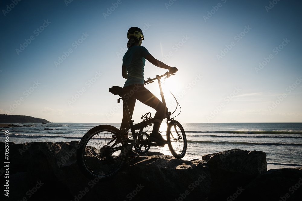 Fototapeta premium Riding folding bike on sunrise seaside road