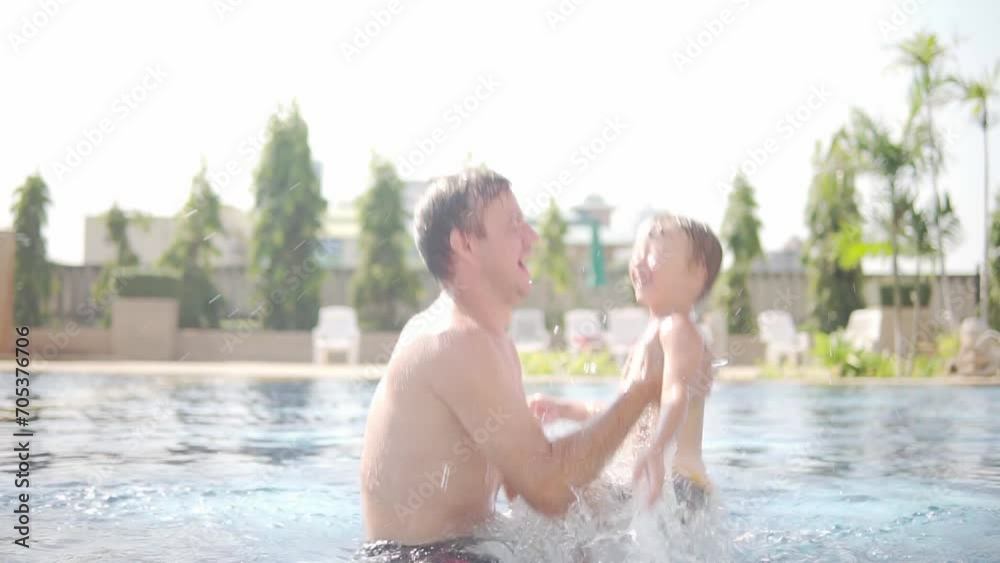 Little boy and his father are frolicking in swimming pool