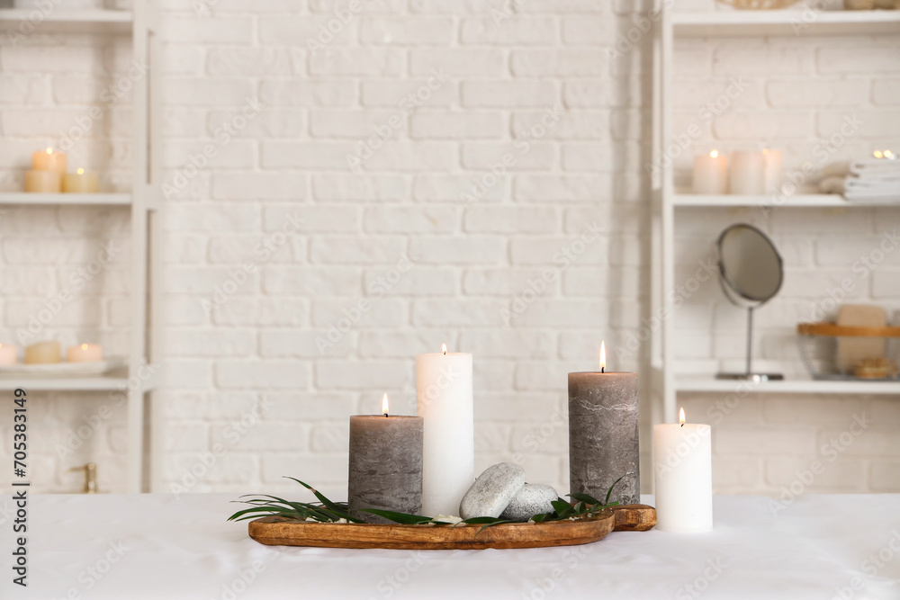 Fototapeta premium Spa composition with burning candles on couch in salon, closeup