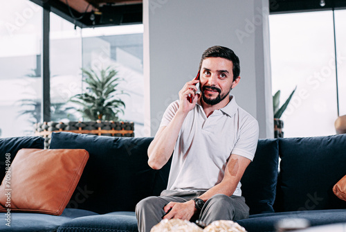 businessman talking on the phone, seated on a sofa in a living room 
