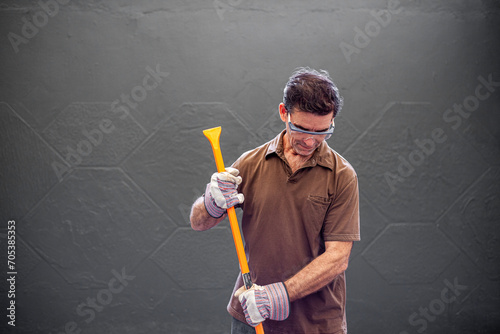 man with gloves and a orange crowbar in his hands working construction with gloves and safety goggles